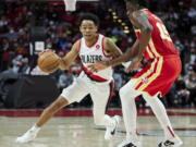 Portland Trail Blazers guard Anfernee Simons, left, dribbles around Atlanta Hawks center Clint Capela during the second half of an NBA basketball game in Portland, Ore., Monday, Jan. 3, 2022.