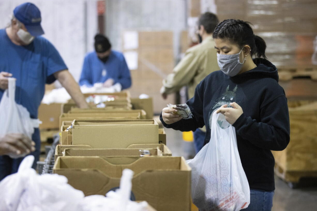 Volunteer Ana Willis fills a bag with food items for the backpack program at Feeding America food bank in Elizabethtown, Ky., Monday, Jan. 17, 2022. Food banks across the country are experiencing a critical shortage of volunteers as the omicron variant frightens people away from group activities.