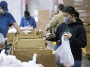 Volunteer Ana Willis fills a bag with food items for the backpack program at Feeding America food bank in Elizabethtown, Ky., Monday, Jan. 17, 2022. Food banks across the country are experiencing a critical shortage of volunteers as the omicron variant frightens people away from group activities.