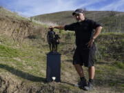 Dan Medina stands next to a statue he created in memory of former Los Angeles Lakers NBA basketball player Kobe Bryant and his daughter, Gianna, on Wednesday, Jan. 26, 2022, in Calabasas, Calif. The statue was carried by the artist on a trail near where Bryant, his daughter, and seven other people died in a helicopter crash two years ago Wednesday.