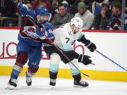 Colorado Avalanche center Nazem Kadri, left, fights for control of the puck with Seattle Kraken right wing Jordan Eberle in the second period of an NHL hockey game Monday, Jan. 10, 2022, in Denver.