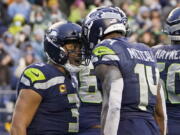 Seattle Seahawks quarterback Russell Wilson, left, reacts with wide receiver DK Metcalf (14) after he passed Metcalf for a touchdown against the Detroit Lions during the second half of an NFL football game, Sunday, Jan. 2, 2022, in Seattle.