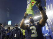 Seattle Seahawks quarterback Russell Wilson gives autographs after a game against the Detroit Lions, Sunday.