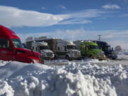 Semitrucks are seen parked near Interstate 90 in Ellensburg, Wash., on Friday, Jan. 7, 2022. The Snoqualmie Pass remained closed as of Friday due hazardous driving conditions.