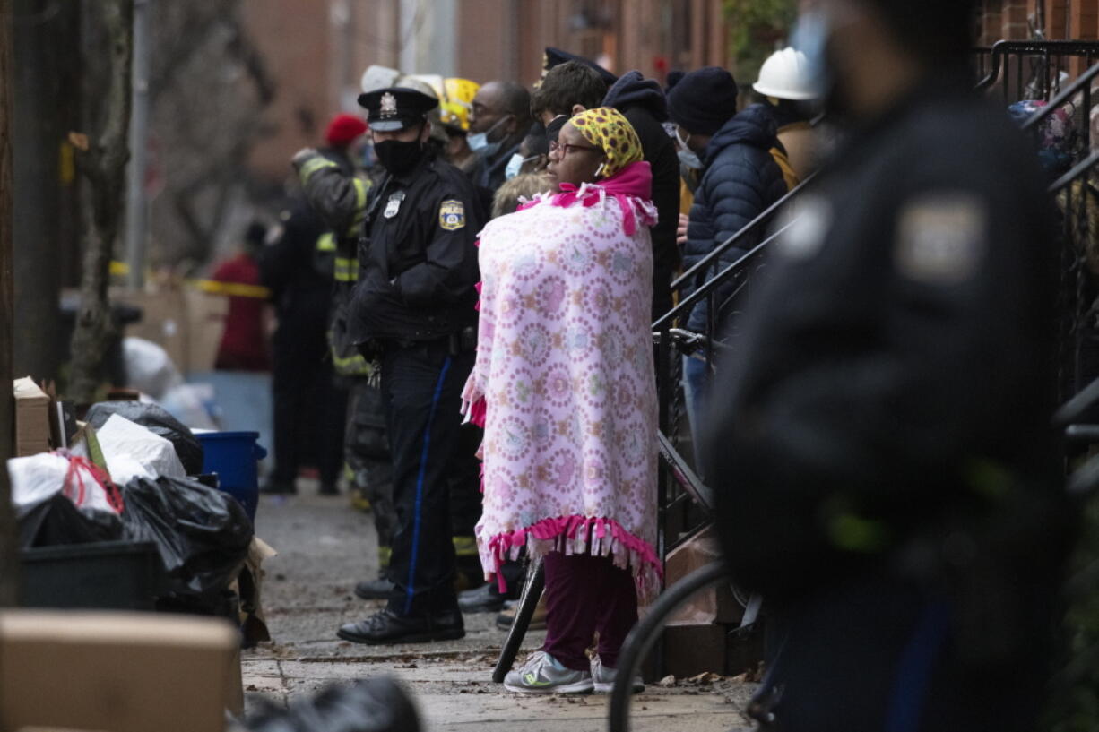 Bystanders watch as the Philadelphia fire department works at the scene of a deadly row house fire in Philadelphia on Wednesday, Jan. 5, 2022. Firefighters and police responded to the fatal fire at a three-story rowhouse in the city's Fairmount neighborhood around 6:40 a.m. and found flames coming from the second-floor windows, fire officials said. (Alejandro A.