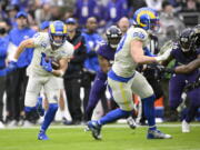 Los Angeles Rams wide receiver Cooper Kupp, left, runs with the ball after making a catch against the Baltimore Ravens during the second half of an NFL football game, Sunday, Jan. 2, 2022, in Baltimore. On the play, Kupp broke the Rams' franchise single season record for most receiving yards after surpassing Isaac Bruce's 1,781 yards set in 1995.