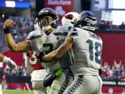 Seattle Seahawks quarterback Russell Wilson, left, celebrates his touchdown run against the Arizona Cardinals with Seattle Seahawks wide receiver Freddie Swain (18) during the second half of an NFL football game Sunday, Jan. 9, 2022, in Glendale, Ariz.