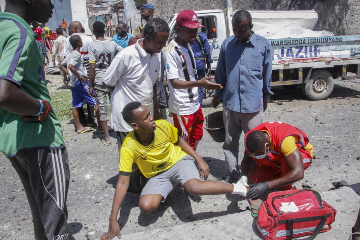 An injured man is treated by a medic at the scene of a blast in Mogadishu, Somalia Wednesday, Jan. 12, 2022. A large explosion was reported outside the international airport in Somalia's capital on Wednesday and an emergency responder said there were deaths and injuries.