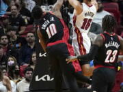 Miami Heat forward Caleb Martin (16) goes to the basket as Portland Trail Blazers guard Dennis Smith Jr. (10) defends during the first half of an NBA basketball game, Wednesday, Jan. 19, 2022, in Miami.