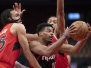 Portland Trail Blazers guard Dennis Smith Jr. (10) drives between Toronto Raptors guard Dalano Banton (45) and forward Scottie Barnes during first-half NBA basketball game action in Toronto, Sunday Jan. 23, 2022.