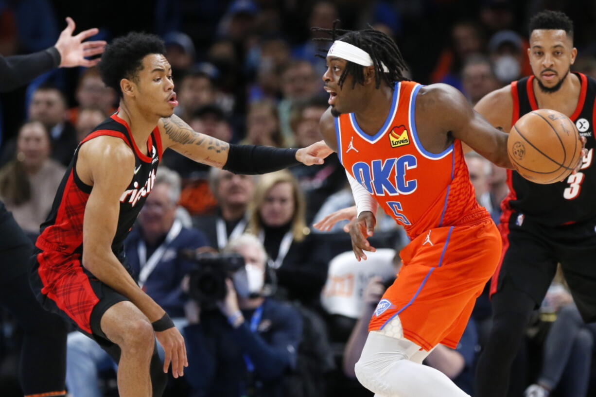 Oklahoma City Thunder guard Luguentz Dort (5) looks to pass the ball around Portland Trail Blazers guard Anfernee Simons, left, in the first half of an NBA basketball game Monday, Jan. 31, 2022, in Oklahoma City.