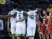 Oregon guard De'Vion Harmon (5) celebrates with Will Richardson (0) and Jacob Young (42) during the second half of the team's NCAA college basketball game against Utah in Eugene, Ore., Saturday, Jan. 1, 2022.