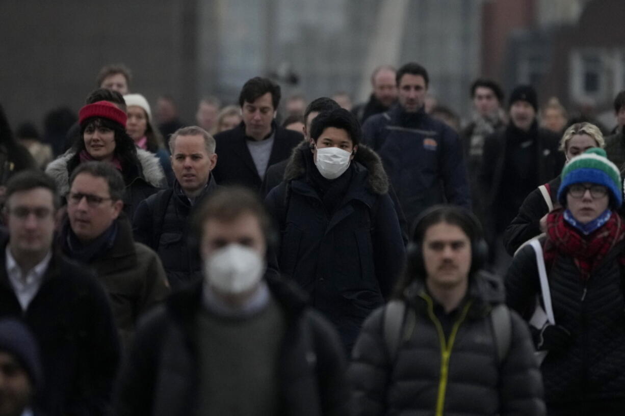 Workers walk over London Bridge towards the City of London financial district during the morning rush hour, in London, Monday, Jan. 24, 2022. The British government have asked people to return to working in offices starting Monday as they ease coronavirus restrictions.