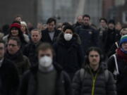 Workers walk over London Bridge towards the City of London financial district during the morning rush hour, in London, Monday, Jan. 24, 2022. The British government have asked people to return to working in offices starting Monday as they ease coronavirus restrictions.