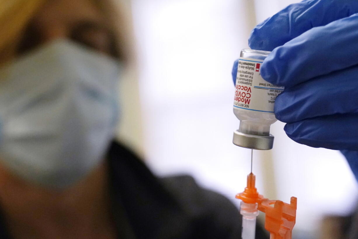 FILE - Pharmacist Kenni Clark prepares a booster dose of the Moderna COVID-19 vaccine during a vaccination clinic at City of Lawrence's "The Center," which serves seniors, families and the community, Wednesday, Dec. 29, 2021, in Lawrence, Mass.  U.S. regulators, on Friday, Jan. 7, 2022,  are shortening the time that people who received Moderna's COVID-19 vaccine have to wait for a booster -- to five months rather than six.