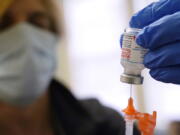 FILE - Pharmacist Kenni Clark prepares a booster dose of the Moderna COVID-19 vaccine during a vaccination clinic at City of Lawrence's "The Center," which serves seniors, families and the community, Wednesday, Dec. 29, 2021, in Lawrence, Mass.  U.S. regulators, on Friday, Jan. 7, 2022,  are shortening the time that people who received Moderna's COVID-19 vaccine have to wait for a booster -- to five months rather than six.