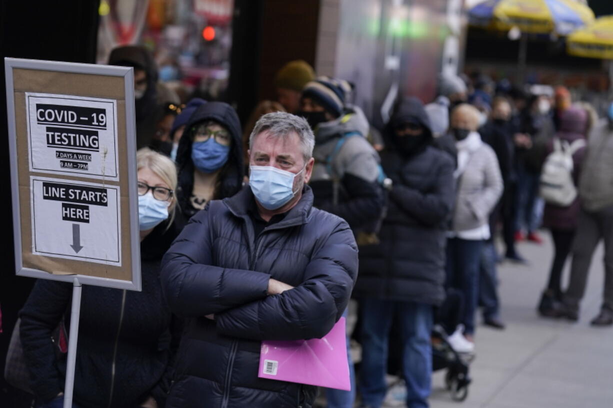 FILE - People wait in line at a COVID-19 testing site in Times Square, New York, Monday, Dec. 13, 2021. Scientists are warning that omicron's lightning-fast spread across the globe practically ensures it won't be the last worrisome coronavirus variant. And there's no guarantee the next ones will cause milder illness or that vaccines will work against them.