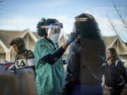 FILE - Maya Goode, a COVID-19 technician, performs a test on Jessica Sanchez outside Asthenis Pharmacy in Providence, R.I., Dec. 7, 2021. Scientists are seeing signals that COVID-19?s alarming omicron wave may have peaked in Britain and is about to do the same in the U.S., at which point cases may start dropping off dramatically.