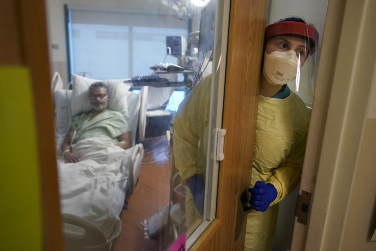 Registered nurse Rachel Chamberlin, of Cornish, N.H., right, steps out of an isolation room where where Fred Rutherford, of Claremont, N.H., left, recovers from COVID-19 at Dartmouth-Hitchcock Medical Center, in Lebanon, N.H., Monday, Jan. 3, 2022. Hospitals like this medical center, the largest in New Hampshire, are overflowing with severely ill, unvaccinated COVID-19 patients from northern New England. If he returns home, Rutherford said, he promises to get vaccinated and tell others to do so, too.