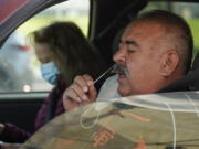 FILE - Jose Alfrtedo De la Cruz and his wife, Rogelia, self-test for COVID-19 at a No Cost COVID-19 Drive-Through event provided the GUARDaHEART Foundation for the City of Whittier community and the surrounding areas at the Guirado Park in Whittier, Calif., on Tuesday, Jan. 25, 2022.  Omicron, the highly contagious coronavirus variant sweeping across the country, is driving the daily American death toll higher than during last fall's delta wave, with deaths likely to keep rising for days or even weeks.