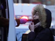 A woman wearing a winter coat gets tested for COVID-19 at a mobile testing site in New York, Jan. 11, 2022. Scientists are seeing signals that COVID-19?s alarming omicron wave may have peaked in Britain and is about to do the same in the U.S., at which point cases may start dropping off dramatically.