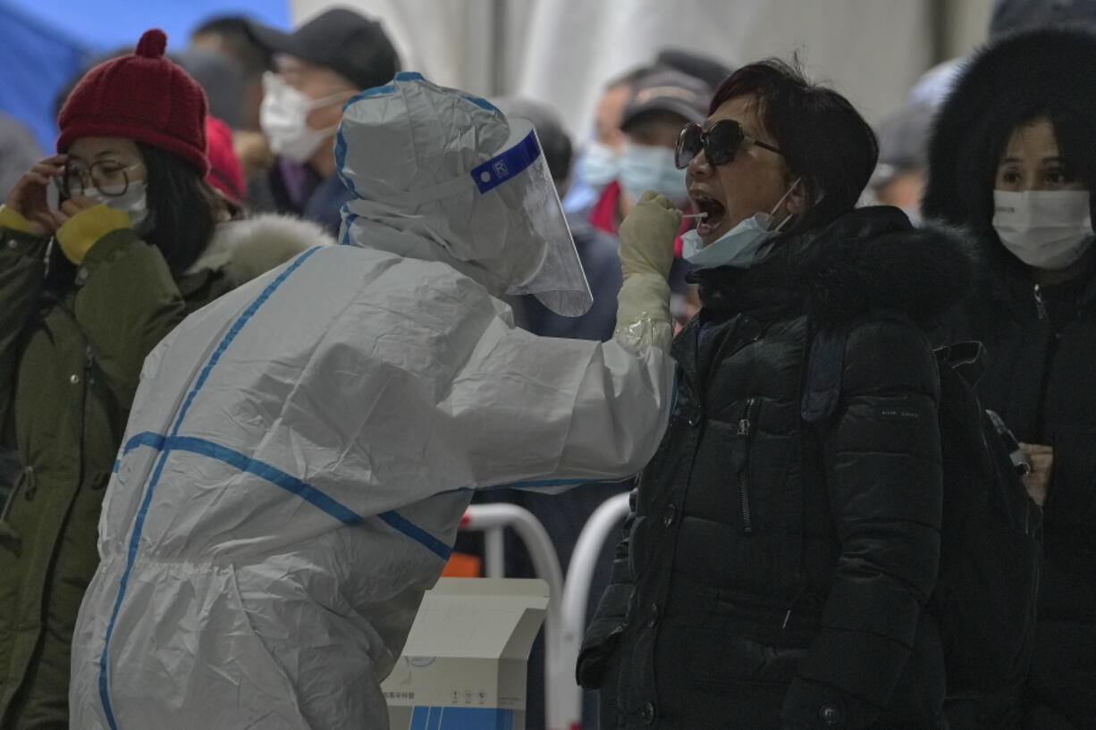 A woman get a throat swab at a mass coronavirus testing site in Beijing, Monday, Jan. 24, 2022. Chinese authorities have lifted a monthlong lockdown of Xi'an and its 13 million residents as infections subside ahead of the Winter Olympics. Meanwhile, the 2 million residents of one Beijing district are being tested following a series of cases in the capital.