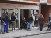 People queue outside a local health center in Madrid, Spain, Tuesday, Jan. 4, 2022. An unprecedented number of coronavirus infections is once again exposing the underfunding and shortcomings of public health care systems, even in developed parts of Europe. Spain is especially feeling the crunch.