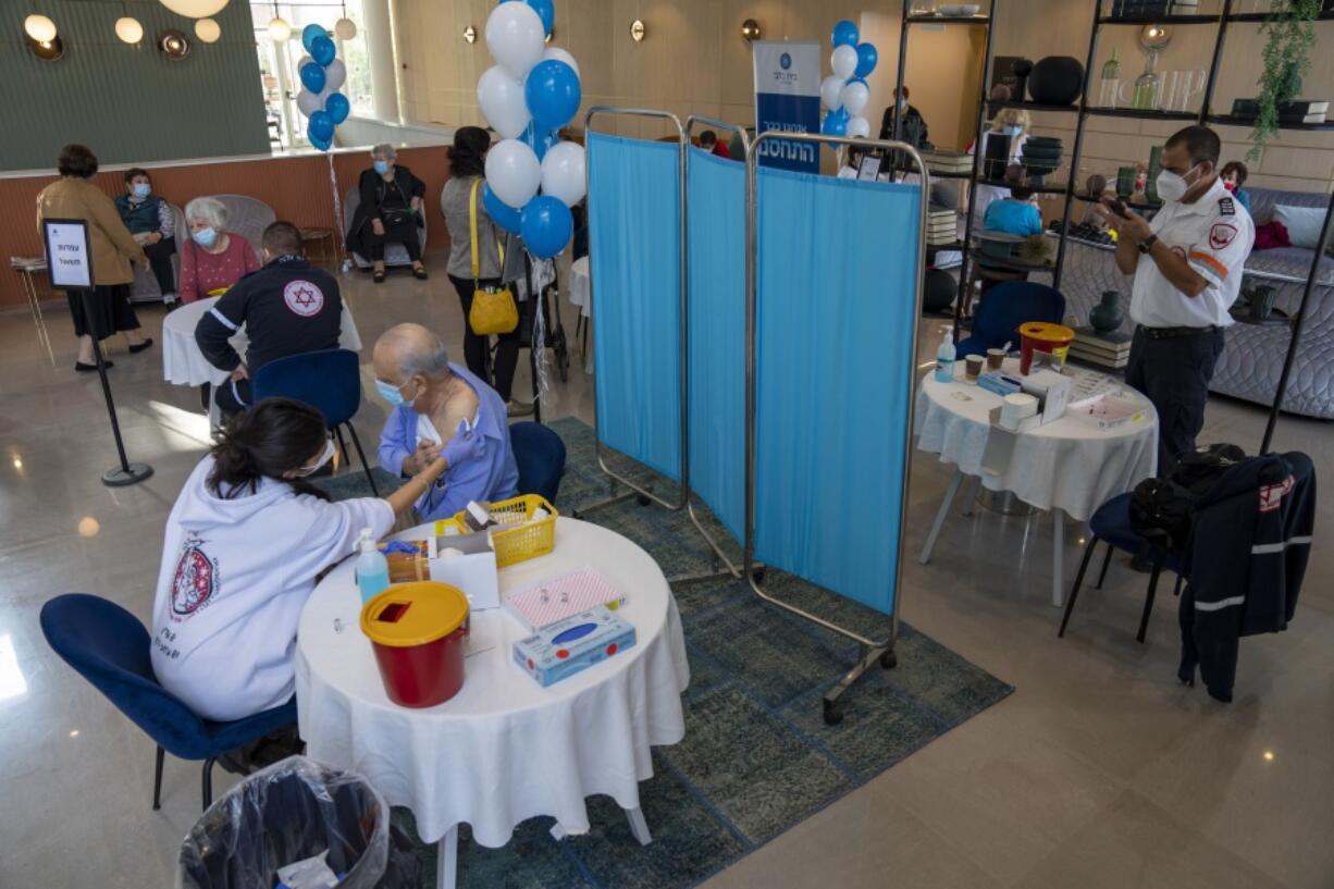 A man receives his fourth dose of the coronavirus vaccine in a private nursing home in Petah Tikva, Israel, Tuesday, Jan. 4, 2022. Even in relatively small, wealthy Israel, an early global leader against the coronavirus pandemic, the omicron variant is outpacing the government's ability to make and execute clear pandemic public policy. What once was a straightforward regimen of vaccines, testing, contact tracing and distancing for the nation of 9.3 million has splintered into a zigzag of rules that seem to change every few days.