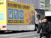 A truck with a public awareness notice on the omicron coronavirus variant moves though a busy shopping street Friday, Jan. 28, 2022, in Tokyo.