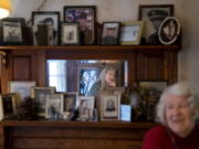 Nancy Rose, center in mirror, speaks with her mother, Amy Russell, right, who both contracted COVID-19 in 2021, in their dining room surrounded by pictures of relatives and family, Tuesday, Jan. 25, 2022, in Port Jefferson, N.Y. More than a third of COVID-19 survivors by some estimates develop lingering problems.