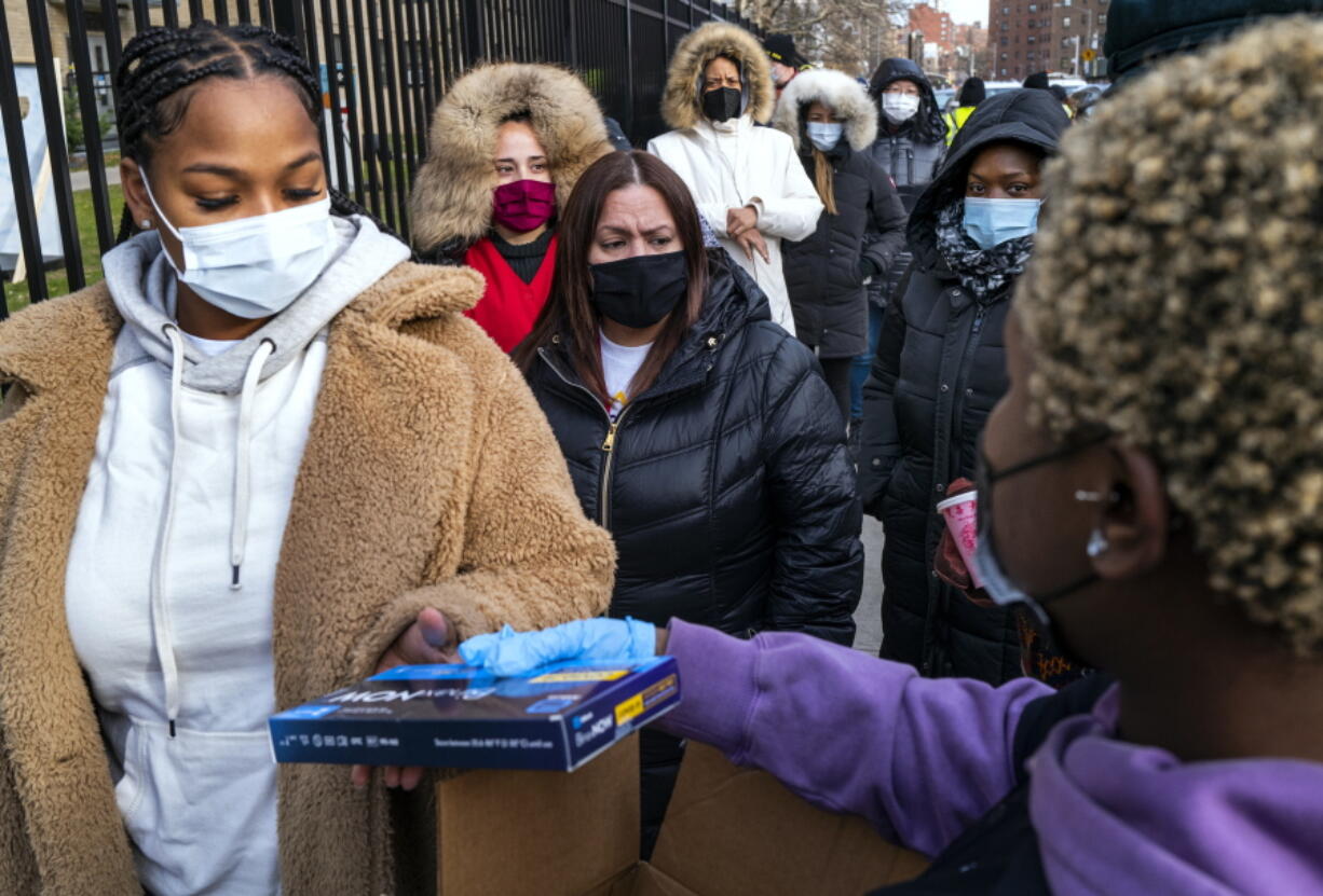 FILE - People line up and receive test kits to detect COVID-19 as they are distributed in New York on Dec. 23, 2021. The COVID-19 surge caused by the omicron variant means once-reliable indicators of the pandemic's progress are much less so, complicating how the media is able to tell the story.