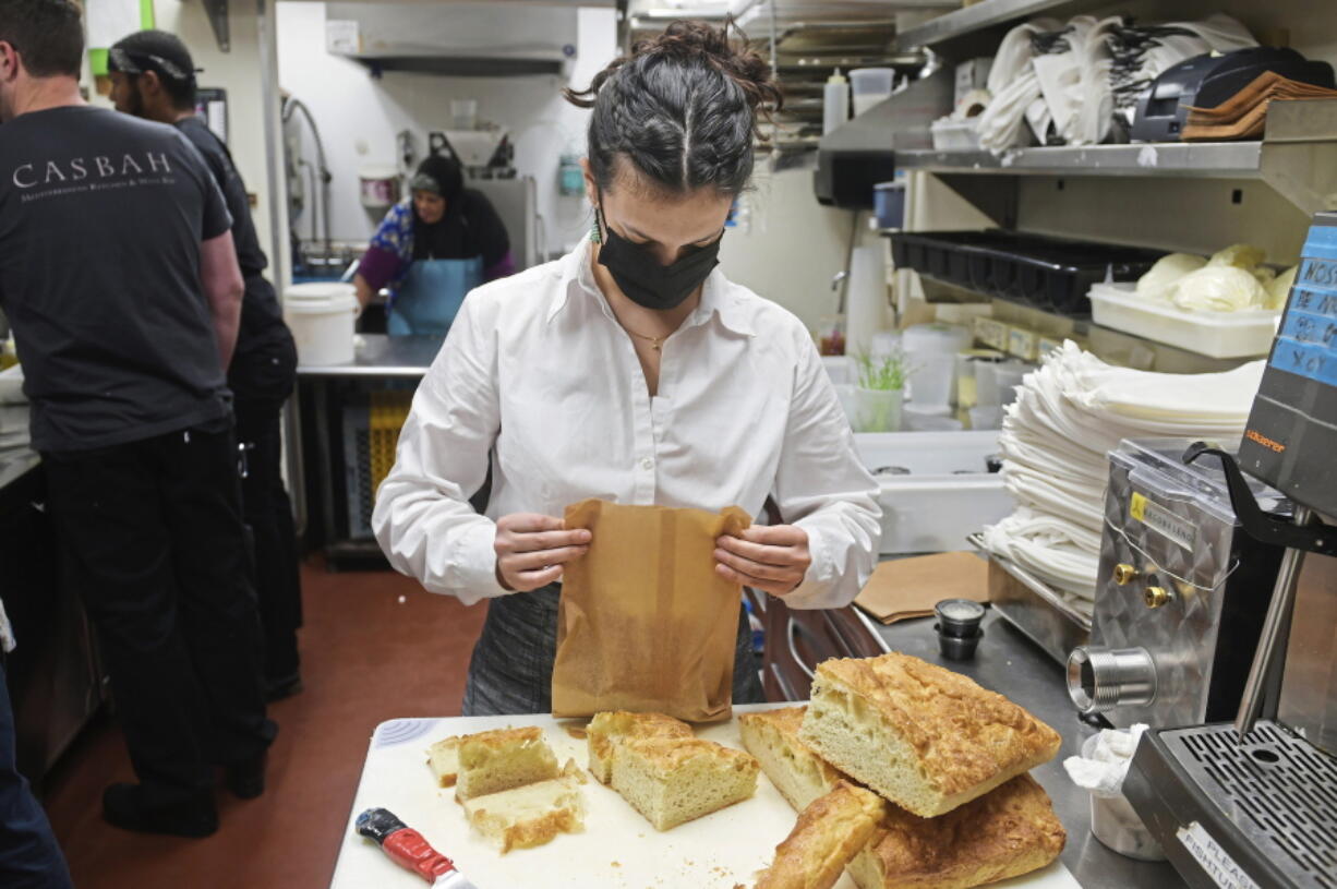 Hailey Shevitz, an employee at Casbah, cuts bread for take-out orders at the restaurant, Wednesday, Dec. 22, 2021, in Shadyside neighborhood in Pittsburgh.