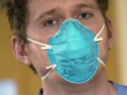 Registered nurse Scott McGieson wears an N95 mask as he walks out of a patient's room in the acute care unit of Harborview Medical Center, Friday, Jan. 14, 2022, in Seattle. Washington Gov. Jay Inslee is deploying 100 members of the state National Guard to hospitals across the state amid staff shortages due to an omicron-fueled spike in COVID-19 hospitalizations. Inslee announced Thursday that teams will be deployed to assist four overcrowded emergency departments at hospitals in Everett, Yakima, Wenatchee and Spokane, and that testing teams will be based at hospitals in Olympia, Richland, Seattle and Tacoma.