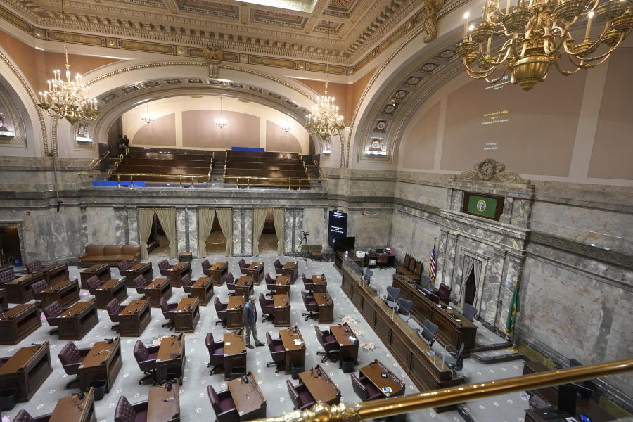 A lone worker walks on the floor of the Washington Senate, Thursday, Jan. 6, 2022, at the Capitol in Olympia. (AP Photo/Ted S.