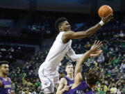 Oregon forward Quincy Guerrier, top, shoots over Washington forward Emmitt Matthews Jr., right, in the first half of an NCAA college basketball game in Eugene, Ore., Sunday, Jan. 23, 2022.