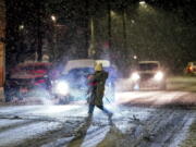 A person carries their dog as they cross Butler Street as snow falls during a winter storm that will impact the region on Sunday night, Jan. 16, 2022, in Lawrenceville a neighborhood in Pittsburgh.