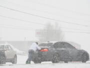 A motorist is pushed through snow by a man on Thursday in Nashville, Tenn. A winter storm blanketed parts of the South with quick-falling snow, freezing rain and sleet Thursday, tying up some roads in Tennessee as the system tracked a path through Appalachia toward the Mid-Atlantic and Northeast.