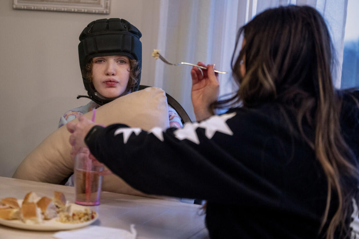 Jessica Berger feeds dinner to her autistic daughter, Zoe Potack, at their Downingtown home Jan. 24, 2022. Families are finding it difficult to find home care for older relatives and disabled children because such workers are in short supply due to the pandemic.