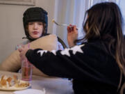 Jessica Berger feeds dinner to her autistic daughter, Zoe Potack, at their Downingtown home Jan. 24, 2022. Families are finding it difficult to find home care for older relatives and disabled children because such workers are in short supply due to the pandemic.