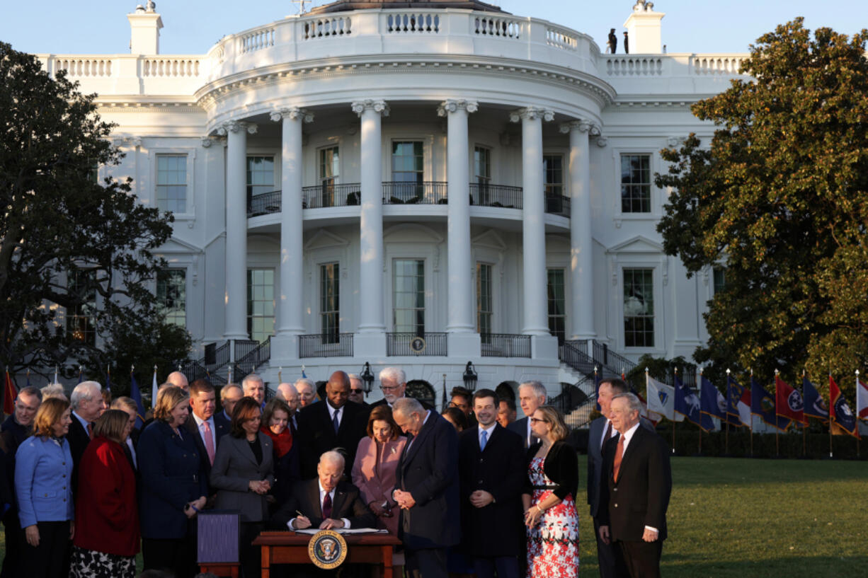 U.S. President Joe Biden signs the Infrastructure Investment and Jobs Act as he is surrounded by lawmakers and members of his Cabinet during a ceremony on the South Lawn at the White House on Nov. 15, 2021, in Washington, D.C.