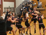 Shelton players mob Tyler Ireland after he made the game-winning shot against Columbia River on Thursday. The 50-48 win by the Shelton ended the Rapids' season.