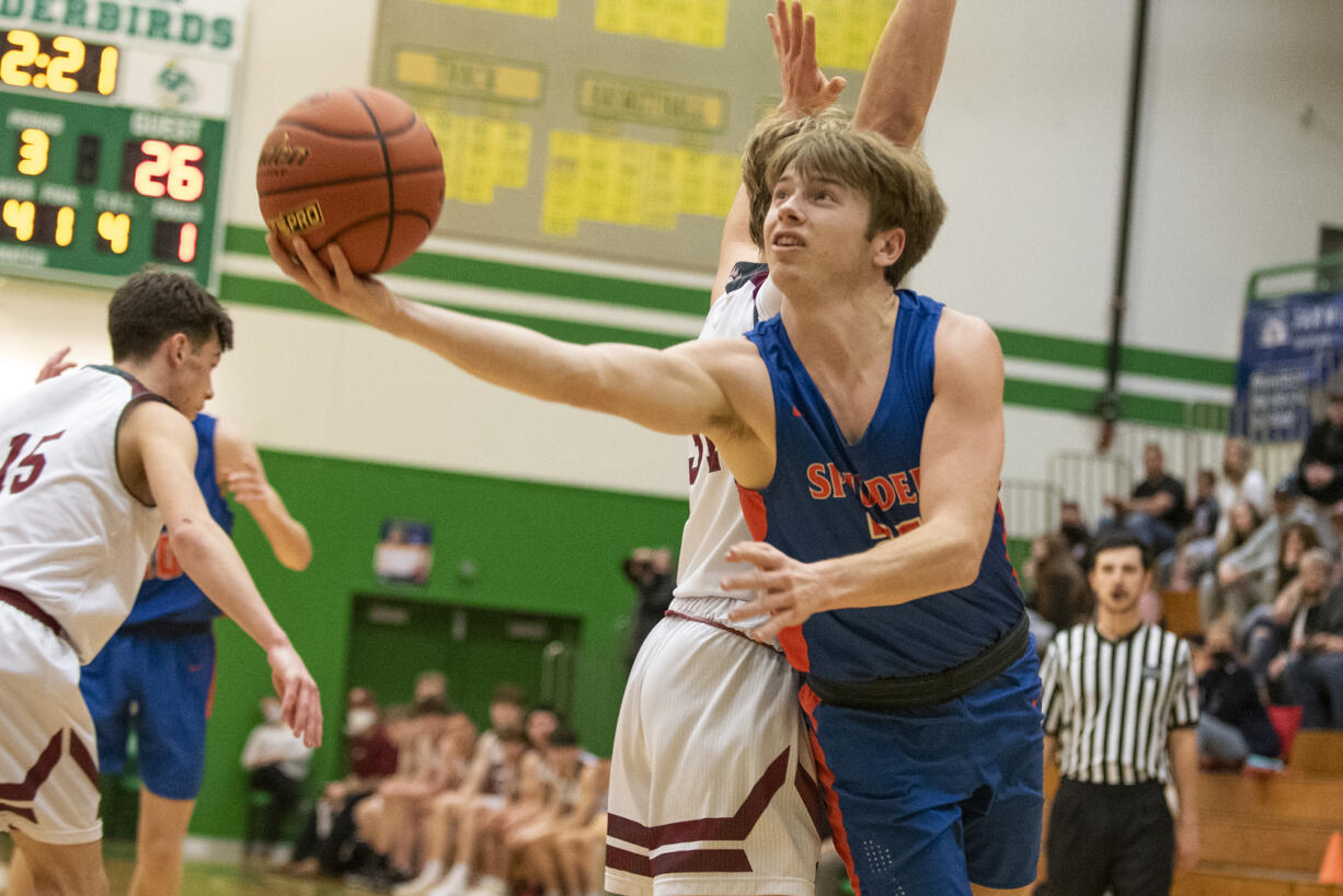 Ridgefield senior Henry Hughes (21) extends for a layup during an elimination loss to W.F. West in the 2A District IV tournament Thursday at Tumwater High School.