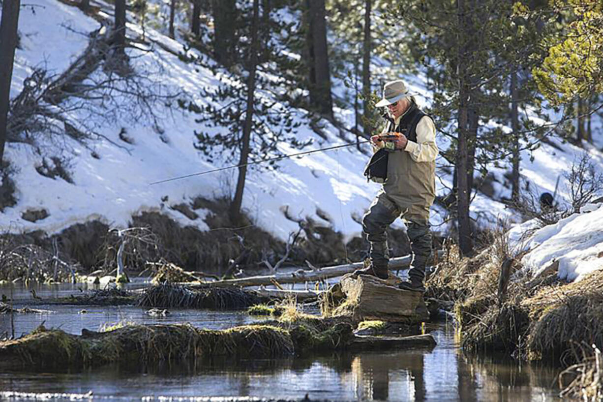 Dave Hickson ties on a new fly after spotting a pod of trout swimming in a deep section of the Fall River on Feb. 12, 2022.