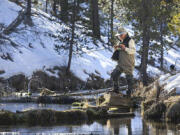 Dave Hickson ties on a new fly after spotting a pod of trout swimming in a deep section of the Fall River on Feb. 12, 2022.