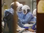 Respiratory therapist Neeru Kaur, right, and other medical staff work on a patient in the COVID-19 Intensive Care Unit at Harborview Medical Center in February.