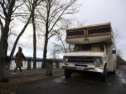 A pedestrian strolls past an abandoned recreational vehicle along Vancouver's Waterfront Renaissance Trail on Tuesday. Derelict vehicles on public property remain a difficult obstacle for towing companies to remove because of their high impound and disposal fee.