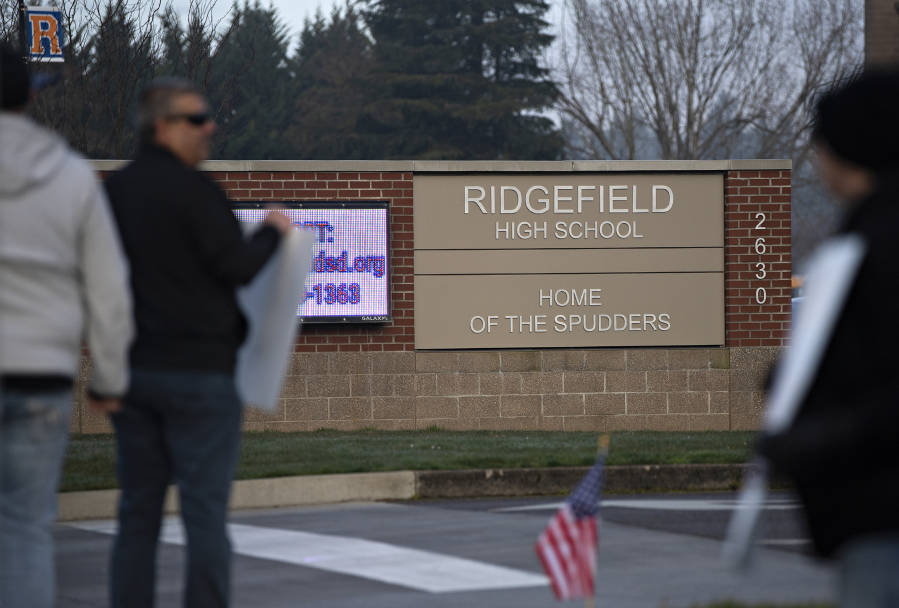 A small group of protesters gathers outside Ridgefield High School to protest mandatory masks in school Wednesday morning.