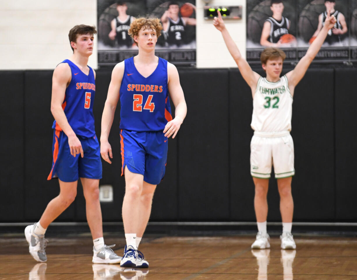 Ridgefield seniors Ty Snider, left, and Joseph Borgmeyer walk off the court while Tumwater senior Adam Overbay celebrates Tuesday, Feb. 15, 2022, after the Spudders' 51-46 loss to Tumwater at Woodland High School.