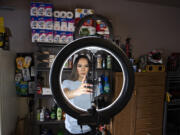 Social media influencer Jeimy Cruz, stands in front of a wall of products as she uses her smartphone to film a post for TikTok at her northeast Vancouver garage.