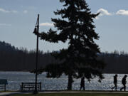 Pedestrians bundle up while taking in a Columbia River view under windy, chilly conditions at the walking path near the Port of Camas Washougal on Tuesday afternoon. Cold temperature records for the day could fall Wednesday.